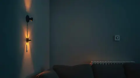 Salon avec une lampe et une prise connectée en fonctionnement, thermostat flou en arrière-plan